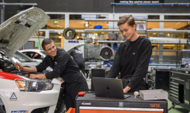 Twee jonge monteurs met elektrische auto en laptop