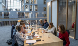 Studenten met laptops aan een gezamenlijke tafel in een instelling
