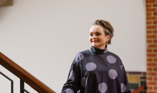 Alexandra van Huffelen staat naast een trap en kijkt lachend langs de camera