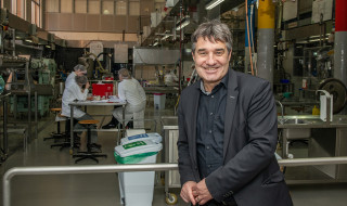 Patrick Cramers in een lab met labmedewerkers op de achtergrond